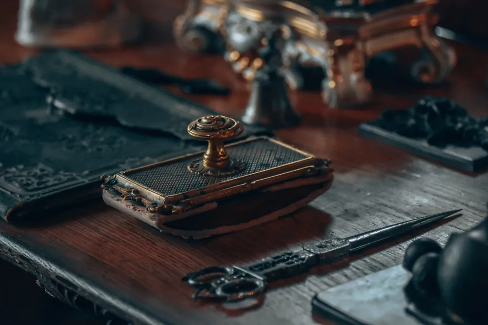 An antique desk with a brass seal and a letter opener