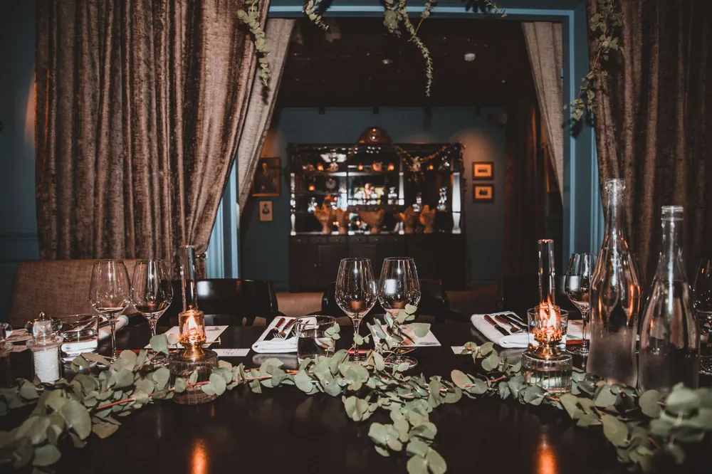 A candlelit dinner table framed by velvet curtains