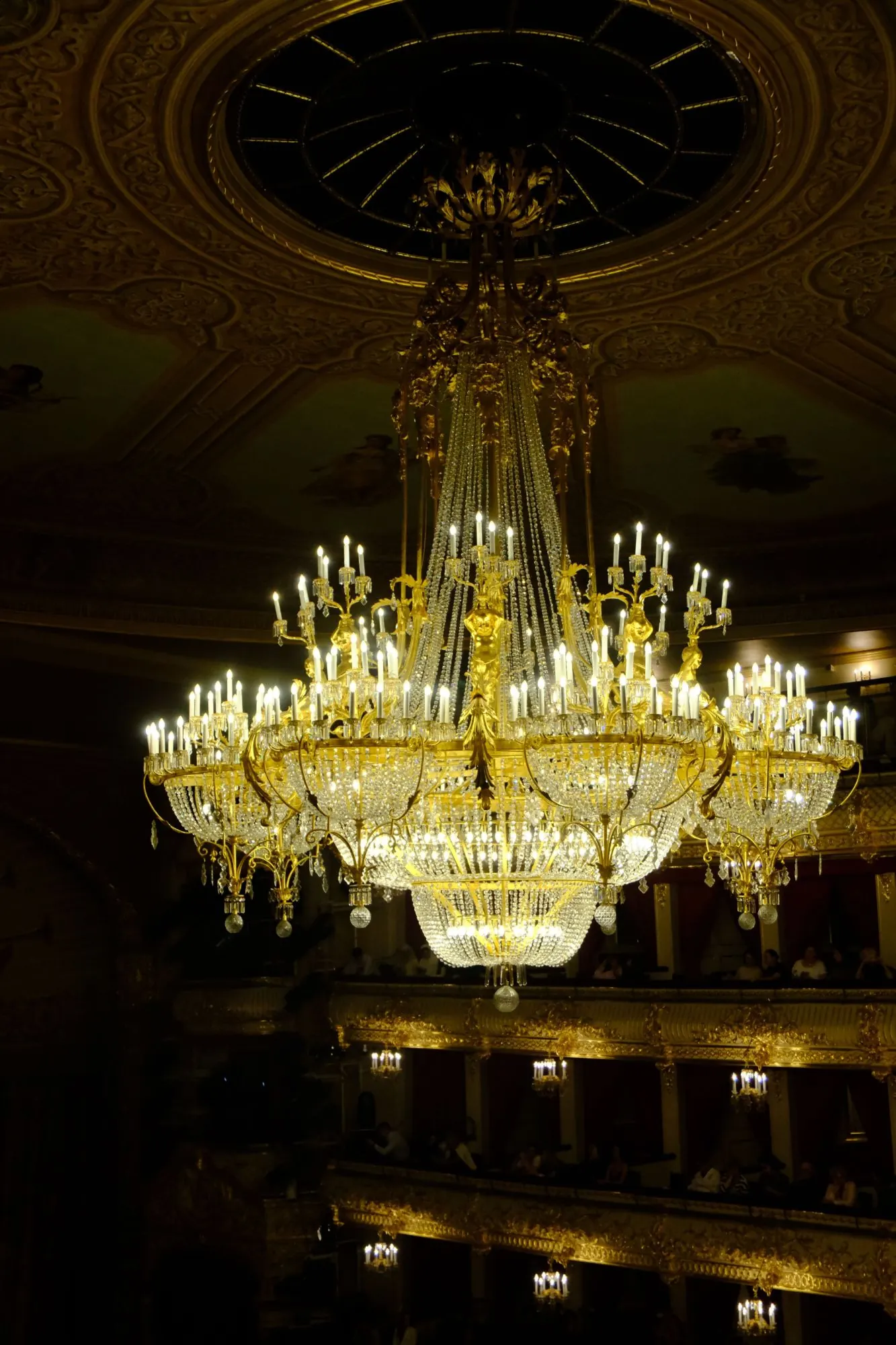 A great chandelier lit above the boxes of an opera house